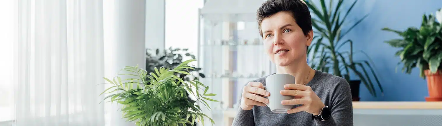 lachende vrouw met op de achtergrond een blauwe muur en 2 planten